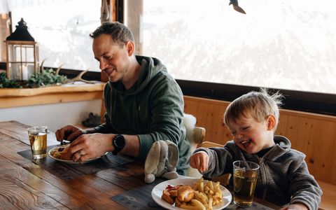 E Guete! Vater und Sohn sitzen am Tisch und essen.