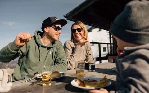 Sonnenterrasse des Bergrestaurants Wiriehorn Familie sitzt am Tisch auf der Sonnenterrasse