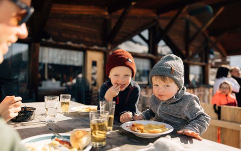 Kinder lieben Pommes Frites Kinder sitzen am Tisch und essen Pommes Frites